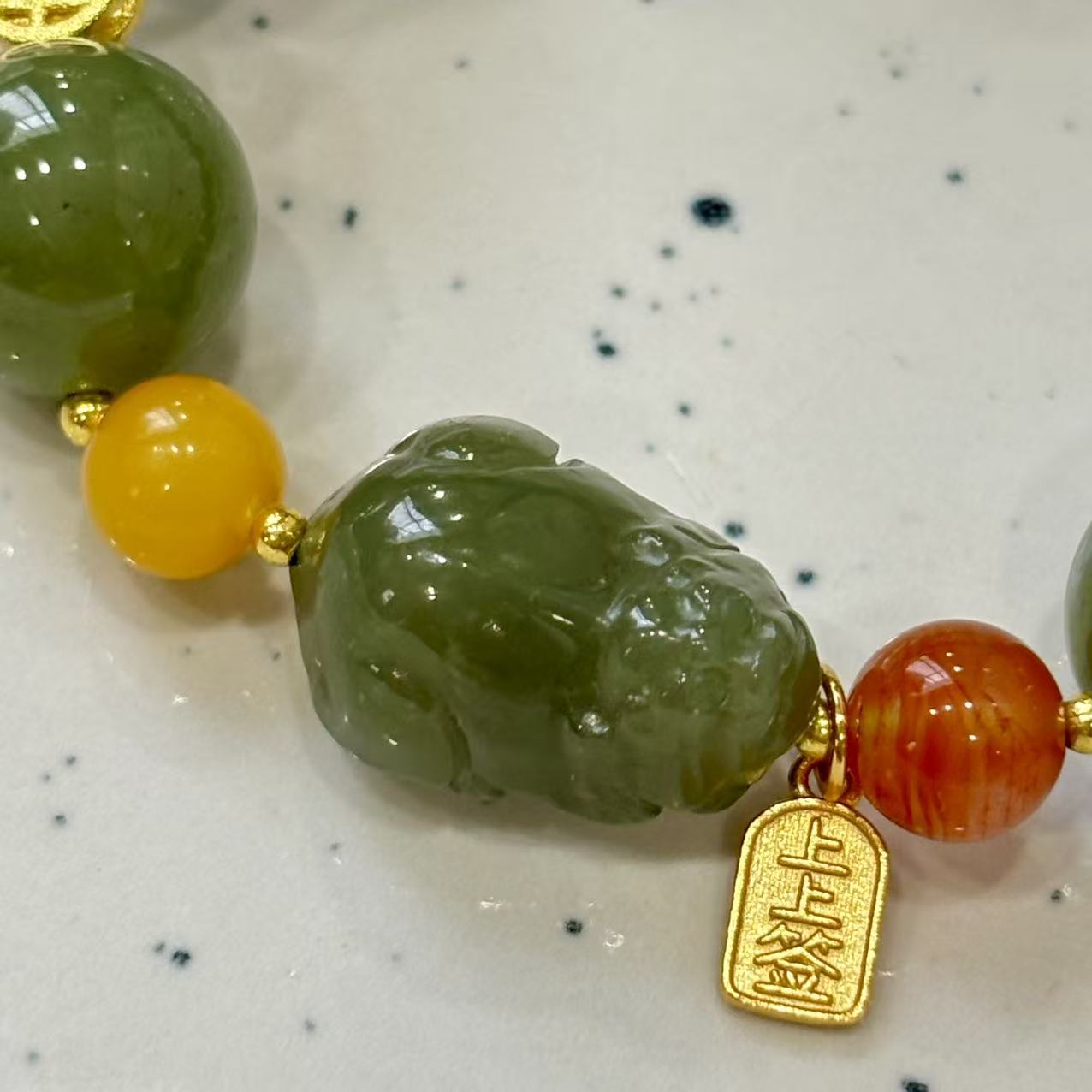 carved Pixiu charm, along with Nanhong agate, silver, amber, and larimar