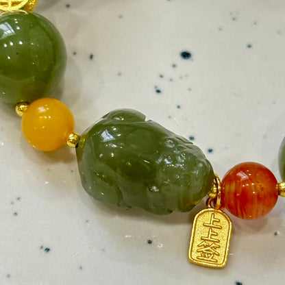 carved Pixiu charm, along with Nanhong agate, silver, amber, and larimar